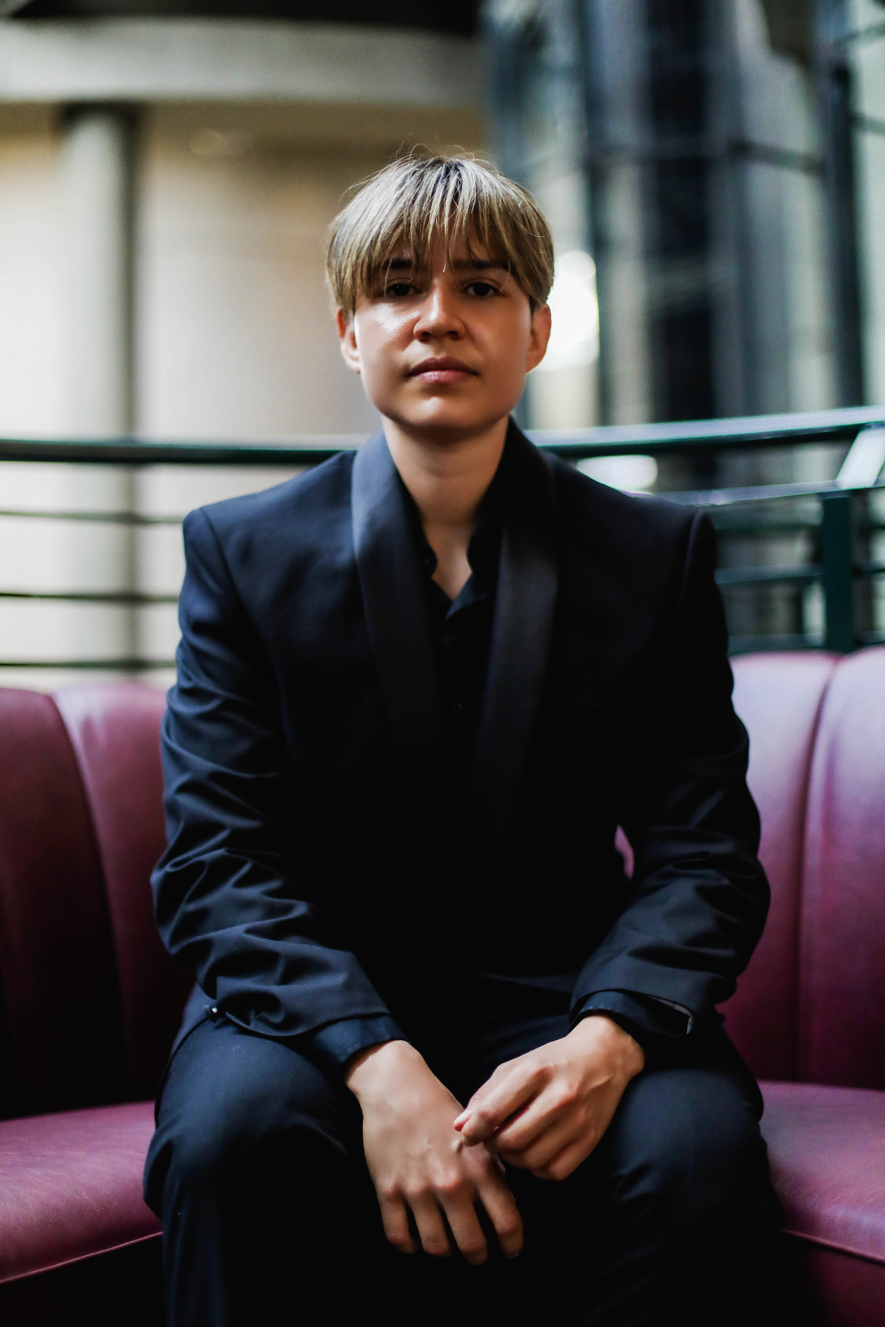 DJ J Moon seated in a dark suit, looking at the camera